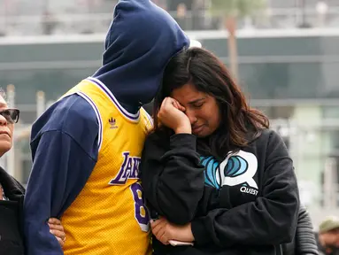 Fans LA Lakers tampak sedih usai Kobe Bryant meninggal dunia di Staples Center, Minggu (26/1/2020). Legenda basket NBA itu wafat dalam kecelakaan helikopter di Calabasas, California. (AFP/Rachel Luna)