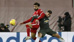 Penyerang Liverpool, Mohamed Salah berebut bola dengan gelandang Manchester United, Bruno Fernandes pada pertandingan lanjutan Liga Inggris di Stadion Anfield, Senin (18/1/2021). MU sekarang memiliki 37 poin sedangkan Liverpool 34. (Phil Noble/Pool via AP)