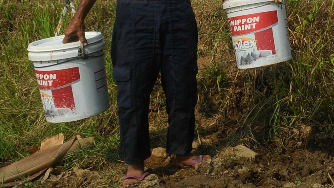 Warga memikul dua ember saat akan mengambil air pada sumber air tersisa di tengah sawah di Kampung Rawa Bogo Kaler, Bogor.