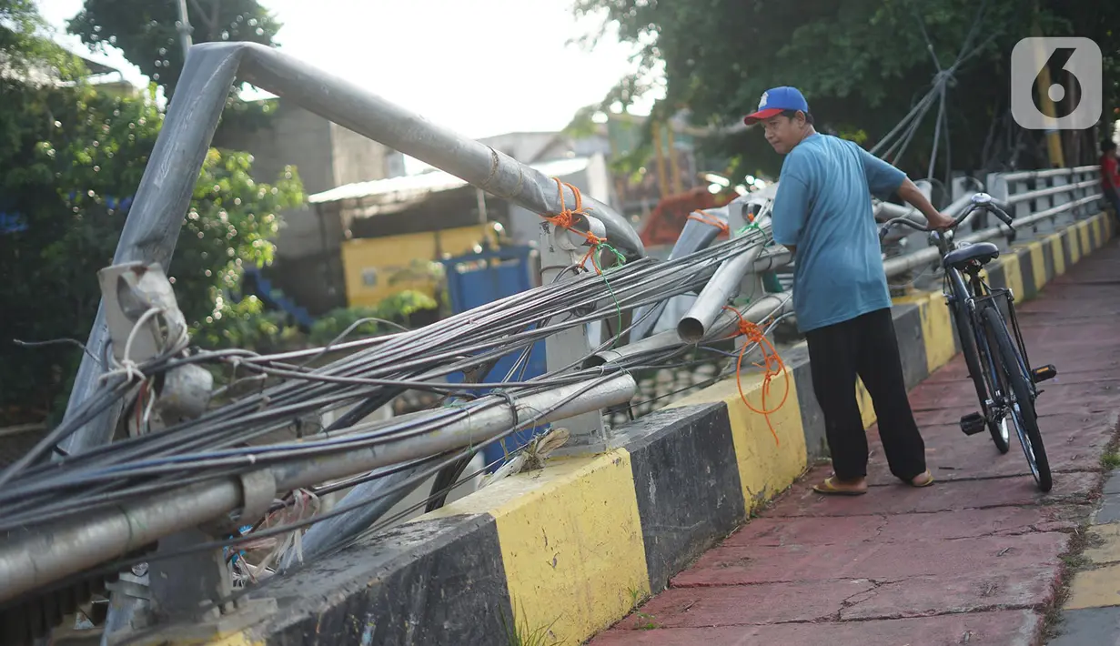 Warga berjalan di samping pagar jembatan yang rusak di kawasan Bukit Duri, Jakarta, Jumat (21/2/2020). Pagar yang rusak akibat penanganan sampah banjir tersebut hingga kini belum juga diperbaiki. (Liputan6.com/Immanuel Antonius)