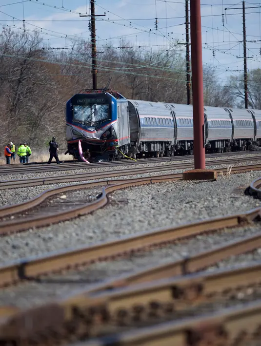 Kereta penumpang Amtrak tergelincir setelah terlibat kecelakaan dengan menabrak backhoe di dekat Philadelphia, Amerika Serikat, Minggu (3/4). Sedikitnya 2 orang tewas dan 30 lainnya mengalami luka-luka akibat kejadian ini. (Mark Makela/Getty Images/AFP)