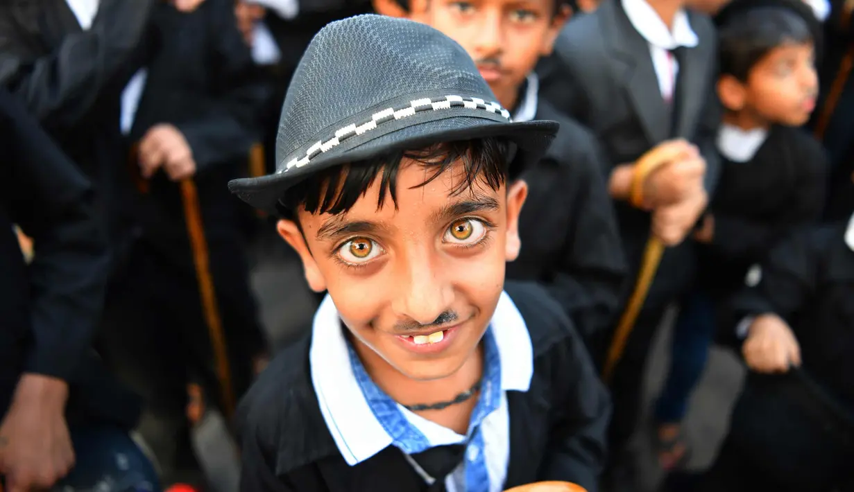 Ekspresi seorang anak berpenampilan seperti Charlie Chaplin berpose memperingati ulang tahun Charlie Chaplin ke-129 di Adipur, sekitar 60 km barat laut Bhuj di negara bagian Gujarat, India barat (16/4). (AFP Photo/Indranil Mukherjee)