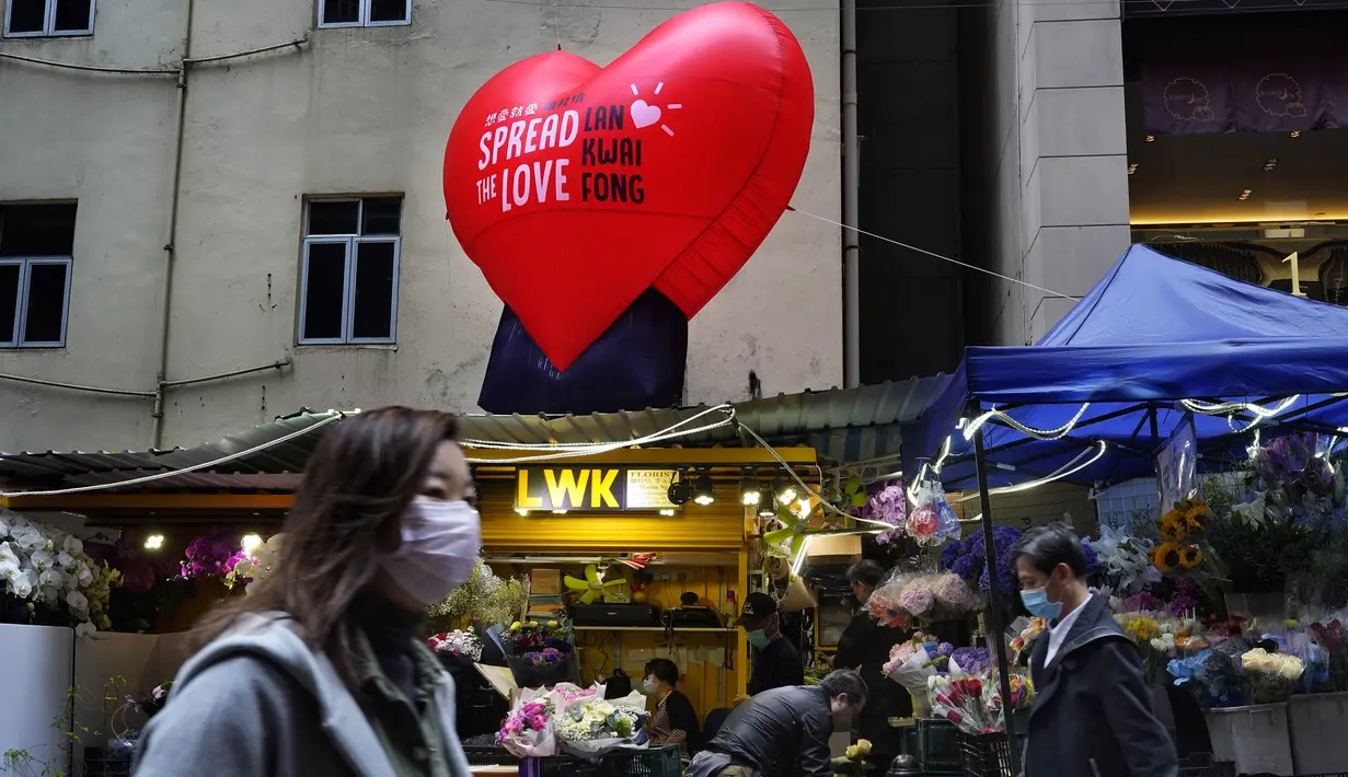 Orang-orang memakai masker berjalan melewati sebuah toko bunga pada Hari Valentine di Hong Kong, Jumat (14/2/2020). China  melaporkan peningkatan tajam dalam jumlah orang yang terinfeksi virus baru, ketika jumlah korban mendekati 1.400. (AP Photo/Vincent Yu)