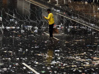 Petugas kebersihan menyapu jalan Medan Merdeka Barat yang dipenuhi sampah usai perayaan hari Buruh Internasional, Jakarta, Senin (5/1). Ribuan massa buruh ikut dalam perayaan Hari Buruh Internasional 2017. (Liputan6.com/Helmi Fithriansyah)