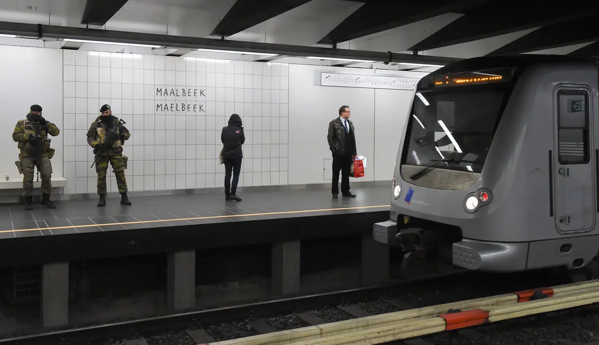 Penumpang berdiri di dekat petugas bersenjata saat menunggu kereta di Stasiun Metro Maelbeek di Brussels, Ibu Kota Belgia, Senin (25/4). Stasiun tersebut akhirnya dibuka kembali setelah serangan bom 22 Maret 2016 yang menewaskan 35 orang. (JOHN Thys/AFP)