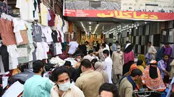 Orang-orang membeli pakaian saat berbelanja menjelang festival Idul Fitri yang akan datang di tengah pandemi corona Covid-19, di Rawalpindi, Pakistan pada 5 Mei 2021. Pusat perbelanjaan ramai oleh warga Pakistan yang berbelanja aneka kebutuhan untuk menyambut Lebaran. (Farooq NAEEM / AFP)