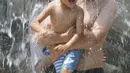 Seorang ayah menggendong anaknya saat bermain air di sebuah taman, Tokyo, (16/7). Badan Meteorologi mengatakan gelombang panas terus berlanjut di wilayah metro ketika suhu naik mencapai 35 derajat Celcius (95 derajat Fahrenheit). (AP Photo/Koji Sasahara)