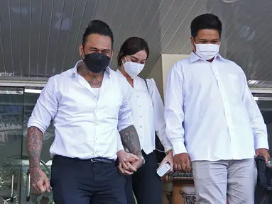 Musikus I Gede Ary Astina alias Jerinx didampingi istrinya, Nora Alexandra (tengah) meninggalkan Polda Metro Jaya, Jakarta, Sabtu (14/8/2021). Polisi memulangkan Jerinx yang sudah menjadi tersangka kasus pengancaman usai bermediasi dengan pengiat sosial Adam Deni. (Liputan6.com/Herman Zakharia)