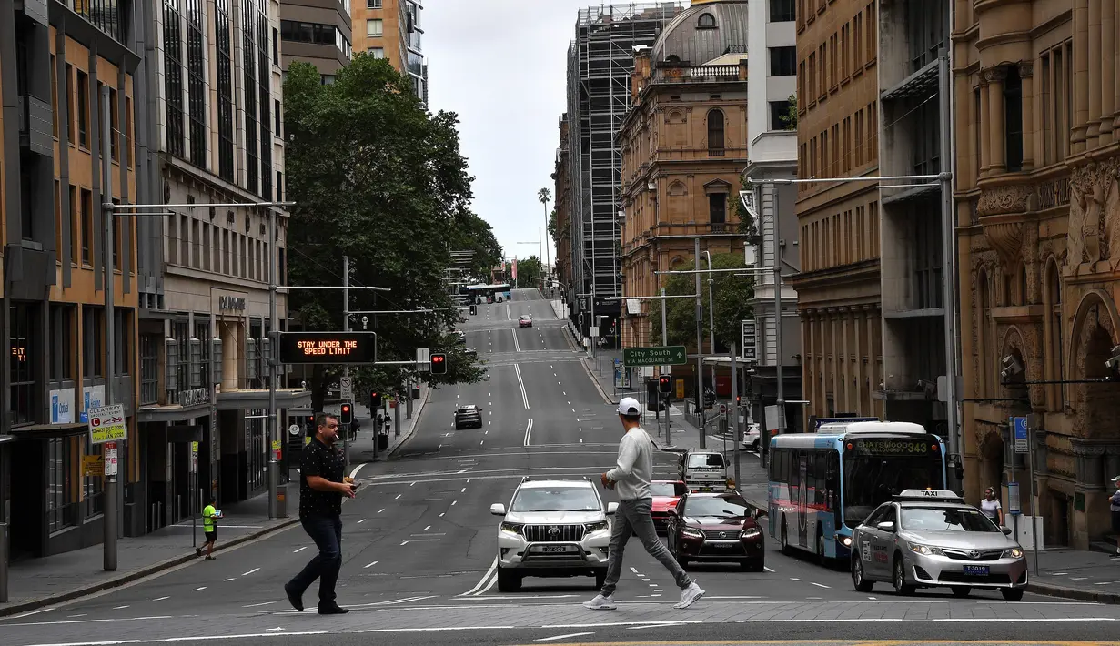 Pejalan kaki melintasi jalan yang biasanya padat dengan lalu lintas di kawasan pusat bisnis di Sydney, Rabu (30/12/2020). Pihak berwenang berupaya menekan klaster kasus virus corona Covid-19 yang terus bertambah di kota terpadat di Australia tersebut. (Saeed KHAN / AFP)