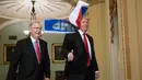 Presiden AS, Donald Trump mengacungkan jempol saat bendera Rusia berukuran kecil dilemparkan ke arahnya di gedung Capitol Hill, Washington DC, Selasa (24/10). Terlihat Trump tengah berjalan bersama senator Mitch McConnel. (AP/J. Scott Applewhite)