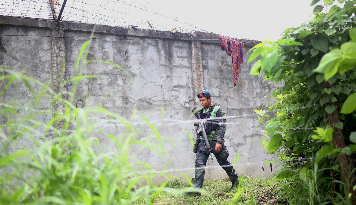 Polisi bersenjata lengkap berpatroli di sekitar pagar parimeter penjara menyusul serangan sekelompok pria bersenjata di kota Kidapawan, selatan Filipina, Rabu (4/1). Disinyalir pelaku penyerangan adalah pemberontak Muslim. (Ferdinandh CABRERA/AFP)