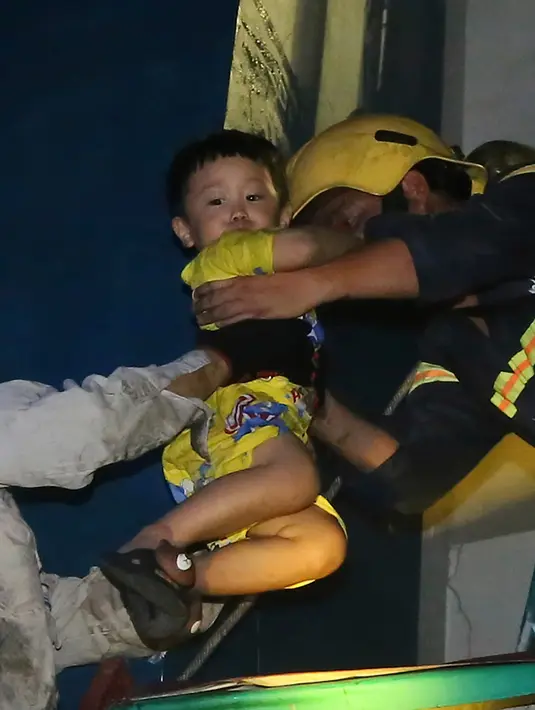 Seorang bocah diselamatkan dari kompleks kondominium selama kebakaran di Kota Ho Chi Minh, Vietnam, (23/3). Kebakaran tersebut menewaskan belasan orang karena kehabisan nafas atau melompat dari lantai tinggi. (VnExpress via AP)