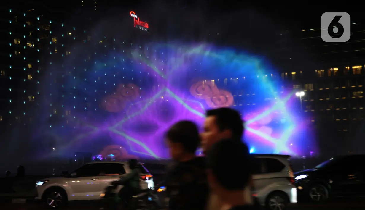 Warga menyaksikan water screen yang sedang di uji coba untuk perayaan malam tahun baru di Bundaran HI, Jakarta, Sabtu (30/12/2023). (merdeka.com/Imam Buhori)