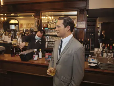 Patung lilin aktor John Hamm dengan memegang minuman berdiri dekat meja bar di Peter Luger Steakhouse, New York, Jumat (26/2/2021). Patung yang dipinjam dari Madame Tussauds itu membantu mengisi meja kosong selama pelonggaran pembatasan aturan COVID-19 makan di dalam ruangan.  (AP Photo/Kevin Hagen)