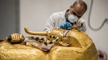 Arkeolog merestorasi sarkofagus atau peti mati emas Firaun Tutankhamun di laboratorium restorasi Grand Egyptian Museum (GEM), Giza, Mesir, Senin (13/4/2020). Firaun Tutankhamun merupakan Raja Mesir Kuno yang memerintah antara tahun 1342-1325 SM. (Khaled DESOUKI AFP)