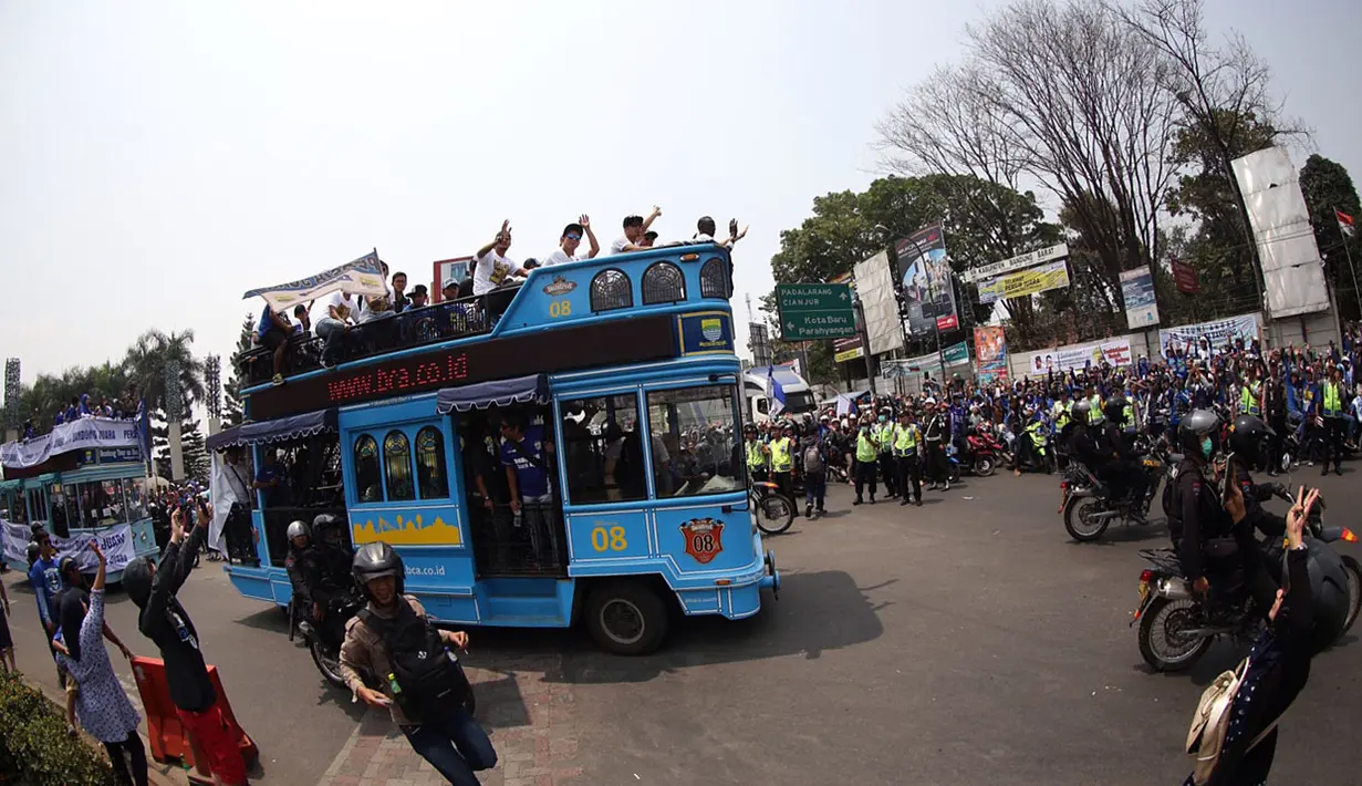 Masyarakat dan bobotoh menyambut pemain Persib diatas Bus Bandung Tour on Bus (Bandros) dalam Pawai Persib Juara Piala Presiden saat start dari Kota Baru Parahyangan, Bandung, Minggu (25/10/2015). (Bola.com/Nick Hanoatubun)