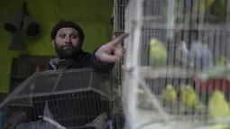 Seorang pemilik toko burung menunjuk burung beonya di pasar burung di Kabul, Afghanistan, Selasa (16/11/2021). Bagi warga Kabul burung dapat membantu membawa bantuan dari tekanan kehidupan di ibukota Afghanistan, yang dilanda serangkaian serangan. (AP Photo/Petros Giannakouris)