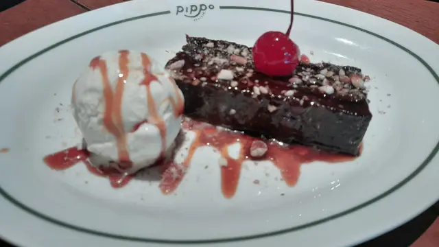 Dessert Bunnet Al Cioccolato yakni sajian manis puding cokelat dengan biskuit dengan vanila gelato di sampingnya.