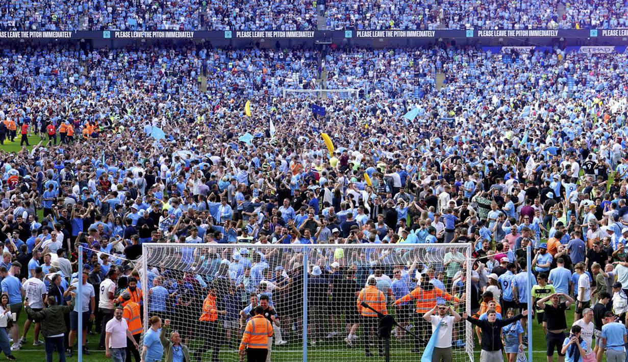 Para suporter tumpah ruah ke lapangan setelah berakhirnya laga antara Manchester City menghadapi Chelsea pada laga lanjutan pekan ke-37 Liga Inggris 2022/2023 di Stadion Etihad, Manchester, Minggu, (21/5/2023). Mereka larut dalam pesta gelar juara Man City. (Martin Rickett/PA via AP)