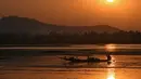 Seorang nelayan Kashmir mengayuh perahunya saat matahari terbenam di danau Dal di Srinagar, India (12/9). Danau Dal dijuluki sebagai Jewel in the Crown of Kashmir atau Srinagar Jewel. (AFP Photo/Tauseef Mustafa)