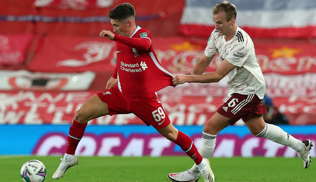 Gelandang Liverpool, Harry Wilson, berebut bola dengan bek Arsenal, Rob Holding, pada laga Piala Liga Inggris di Stadion Anfield, Jumat (2/10/2020) dini hari WIB. Arsenal menang 5-4 atas Liverpool lewat adu penalti. (AFP/Peter Byrne)