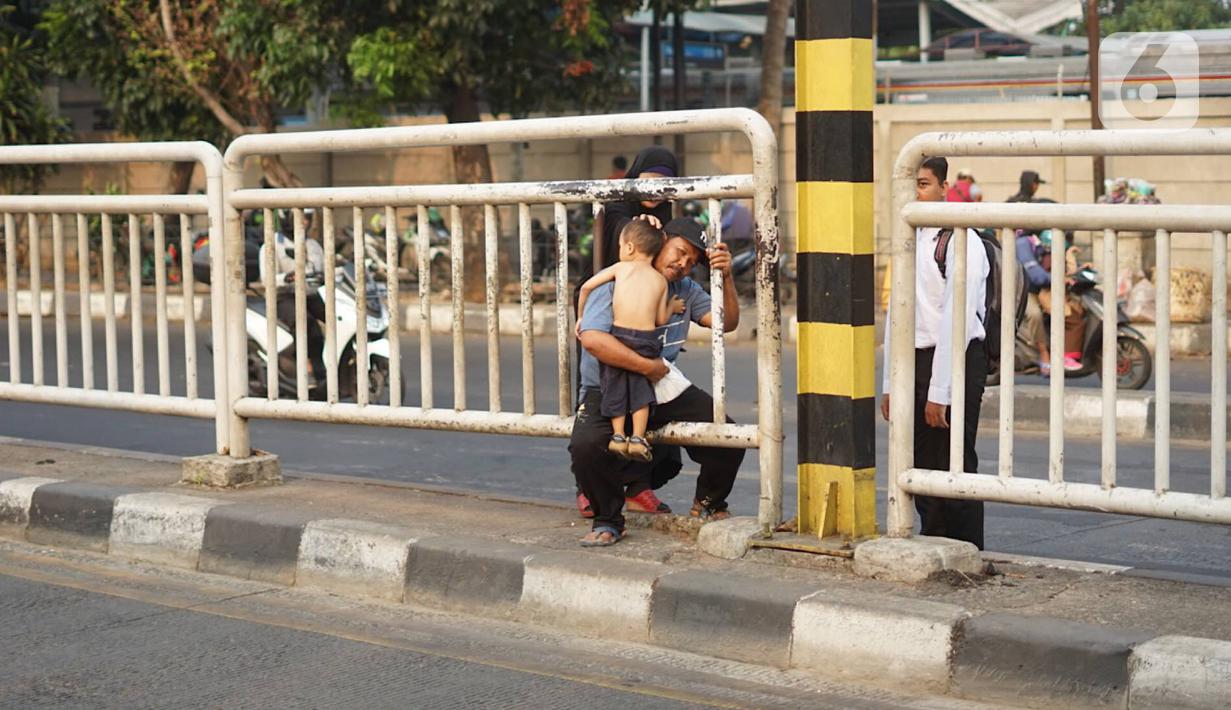 Warga menerobos celah pagar pembatas jalan di depan Stasiun Pasar Minggu, Jakarta, Rabu (16/10/2019). Jauhnya jembatan penyeberangan orang (JPO) membuat warga memanfaatkan celah pagar pembatas tersebut sebagai akses menyeberang, meski berbahaya bagi keselamatan. (Liputan6.com/Immanuel Antonius)