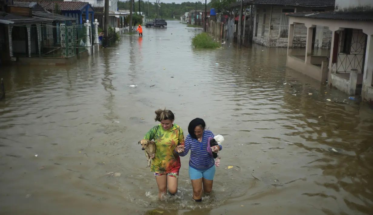 Warga menyeberangi jalan yang tergenang air akibat hujan yang disebabkan oleh Badai Idalia, di Batabano, Kuba, Selasa, 29 Agustus 2023. (AP Photo/Ramon Espinosa)