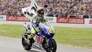 Valentino Rossi membawa bendera bertuliskan angka 100 ketika merayakan kemenangannya yang ke-100 dalam balapan MotoGP di sirkuit Assen pada Juni 2009. (AFP/ANP/Vincent Jannink)