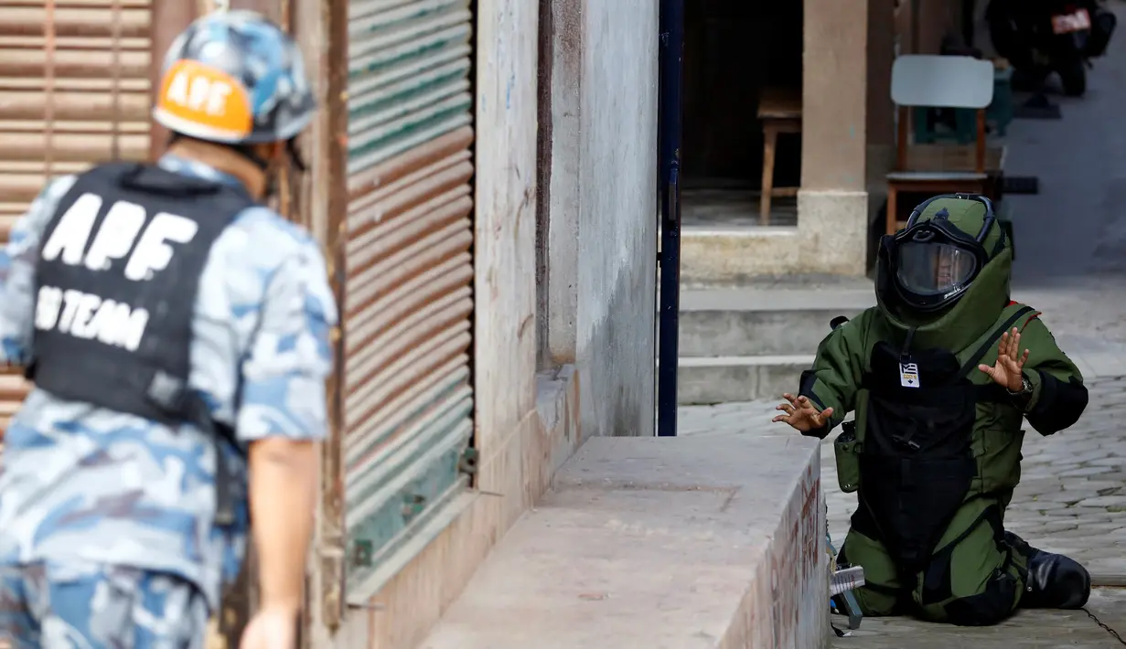 Anggota kepolisian mengenakan pakaian khusus saat menjinakkan bom yang ditemukan di sekitar sekolah di Kathmandu, Nepal, Selasa (20/9). Otoritas berwenang setempat mengabarkan ada 5 sekolah yang ditemukan bom di kota tersebut. (REUTERS/Navesh Chitrakar)