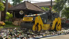 Polisi menggunakan alat berat saat memusnahkan ribuan botor miras di Polres Kota Tangerang Banten, Rabu, (23/12).Polresta Tangerang memusnahkan miras sebanyak 11.155 botol dan 264 Ciu yang berkemas botol mineral. (Liputan6.com/Faisal R Syam)
