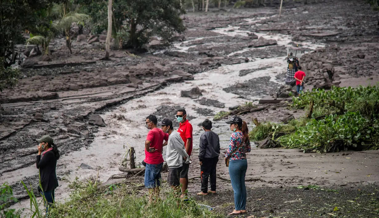 Sejumlah warga melihat aliran lahar dingin Gunung Agung di Karangasem, Bali (29/11). Ribuan turis diperkirakan akan meninggalkan Bali pada 30 November menyusul penutupan bandara akibat Gunung Agung Meletus. (AFP Photo/Juni Kriswanto)
