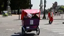 Wisatawan berkeliling kota Paris menggunakan transportasi becak, Prancis, (7/7). Desain becak di Paris ini memiliki posisi penarik becak dibagian depan berbeda dengan becak yang ada di Indonesia. (AFP Photo/Jacques Demarthon)