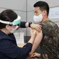 Seorang tentara Korea Selatan menerima dosis pertama vaksin virus corona COVID-19 AstraZeneca di Rumah Sakit Pusat Angkatan Bersenjata, Seongnam, selatan Seoul, Rabu (28/4/2021). Militer Korea Selatan mulai menjalani vaksinasi COVID-19. (Handout/South Korean Defence Ministry/AFP)