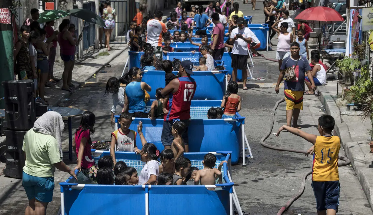 Anak-anak didampingi orang tua bermain di kolam portabel yang diberikan oleh pemerintah setempat untuk mendinginkan tubuh pada saat musim panas di Manila, Filipina (12/4). (AFP Photo/Noel Celis)
