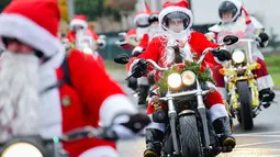 Pengendara motor besar berpakaian seperti Sinterklas menyusuri jalanan selama acara amal di Lustadt, Jerman, Kamis (6/12). Mereka mengumpulkan sumbangan untuk rumah sakit Sterntaler di Speyer, yang merawat anak-anak penderita kanker. (Uwe Anspach/dpa/AFP)