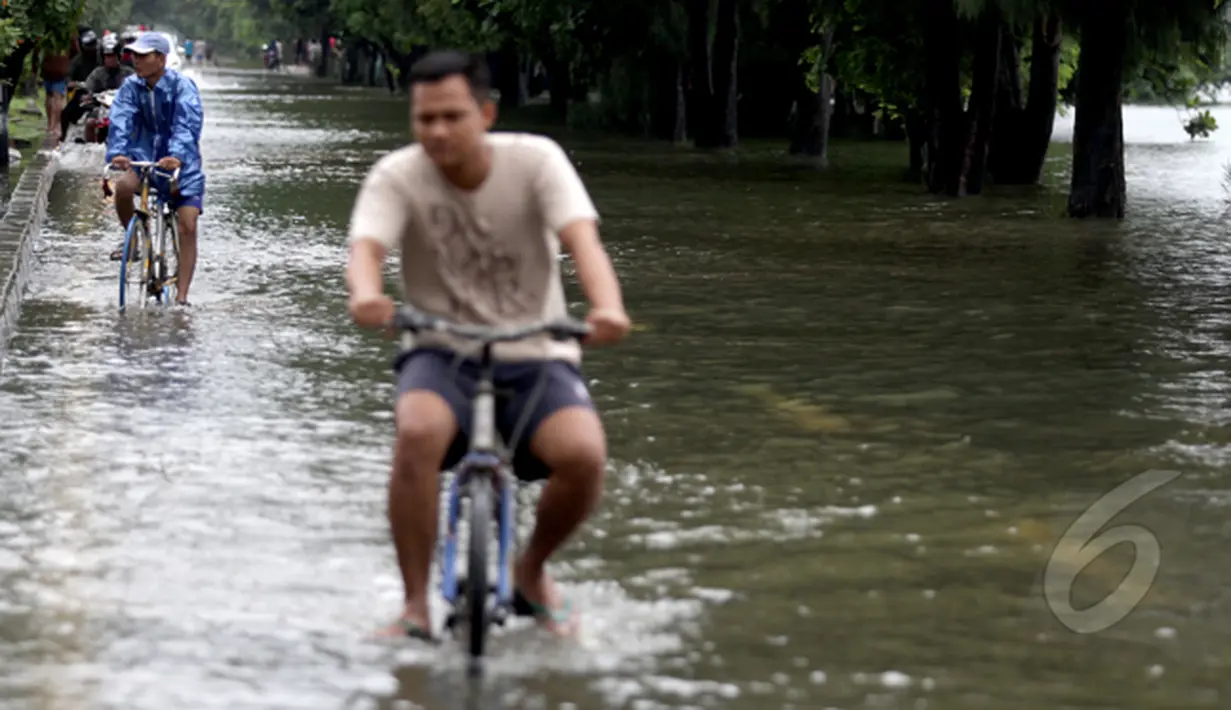 Curah hujan yang tinggi di Jakarta menyebabkan sejumlah kawasan terendam banjir. sejumlah warga melintasi jalan yang terendam air di sekitar Danau Sunter dengan menggunakan sepeda, Jakarta, Selasa (10/2/2015). (Liputan6.com/Faizal Fanani)