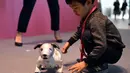 Seorang anak bermain dengan robot anjing dari Sony, Aibo yang telah ia beli saat acara peresmian di Tokyo, Jepang (11/1). Aibo memiliki perilaku yang dapat beradaptasi dengan lingkungan sekitar, ia juga dapat mencari si pemilik. (AFP Photo/Kazuhiro Nogi)