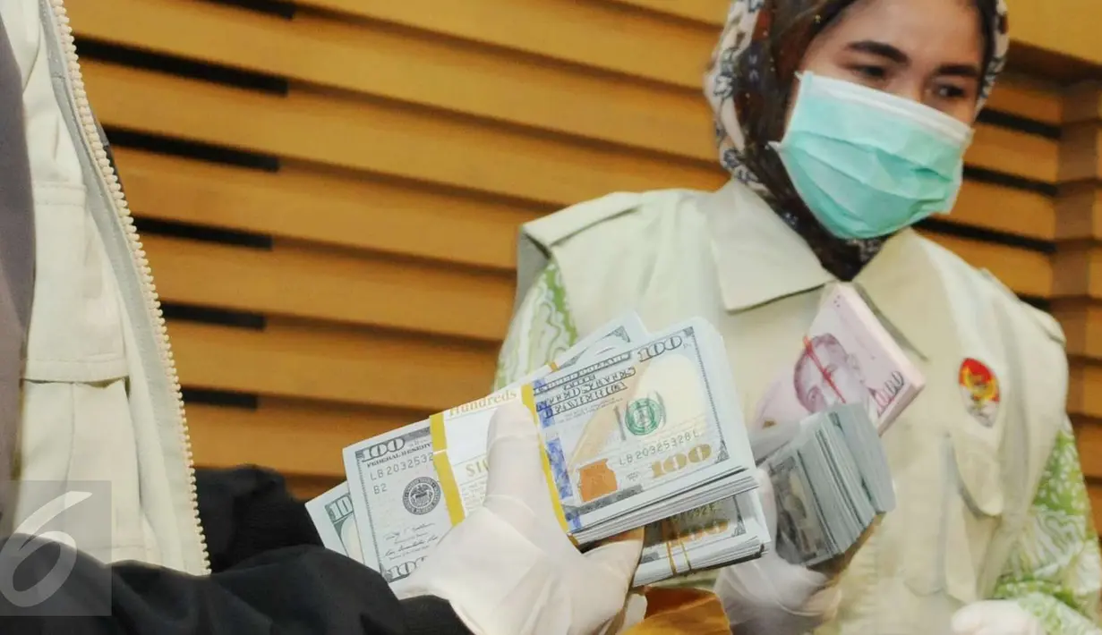 Petugas menunjukkan barang bukti uang saat konferensi pers di Gedung KPK, Jakarta, Kamis (15/12). Terkait OTT yang menjerat Deputi Bakamla, Eko Susilo Hadi, KPK menyita uang Rp 2 miliar dalam pencahan dolar Singapura. (Liputan6.com/Helmi Afandi)
