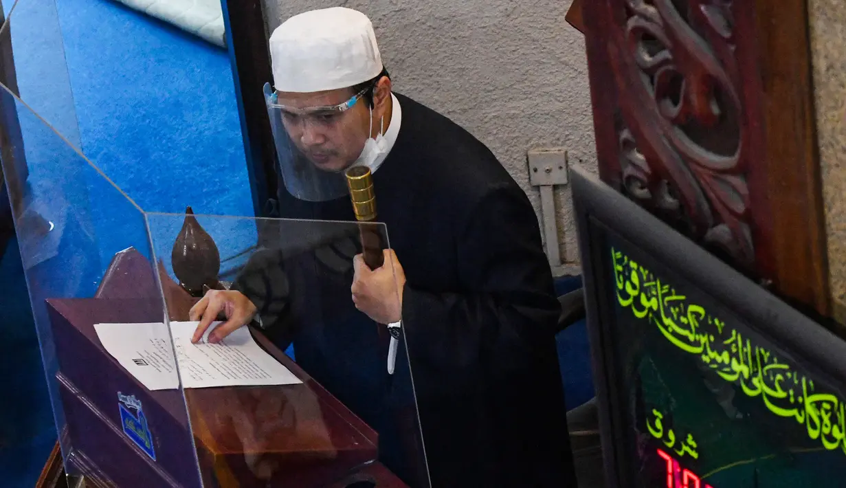 Seorang imam mengenakan pelindung wajah saat khotbah salat Jumat usai pencabutan pembatasan Covid-19 di Masjid Al-Istighfar, Singapura, Jumat (26/6/2020). Masjid-masjid di Singapura menyediakan 2 sesi setiap Jumat dengan kuota yang diperbolehkan adalah 50 orang pada satu waktu. (Roslan RAHMAN/AFP)