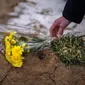 Seorang pria meletakkan bunga di makam seorang kerabatnya dalam upacara peringatan satu tahun dimulainya perang Rusia-Ukraina, di sebuah pemakaman di Bucha, Ukraina, Jumat, 24 Februari 2023. (AP Photo/Emilio Morenatti)