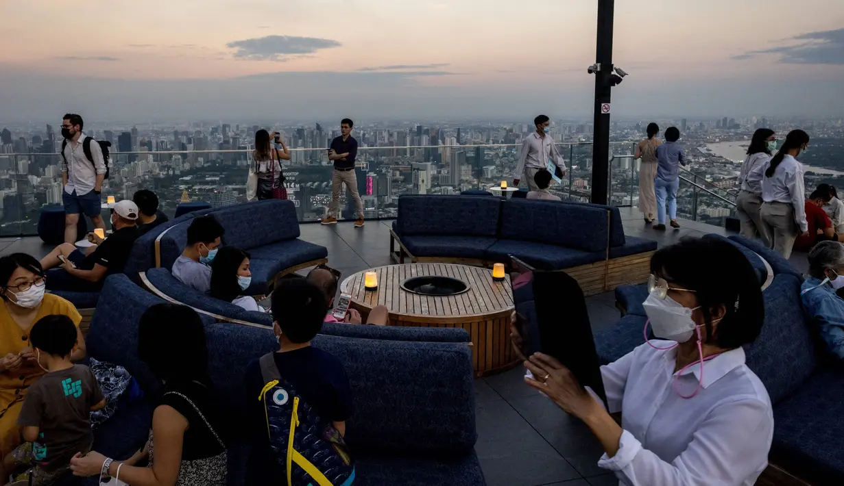 Orang-orang memandangi cakrawala dari dek observasi di gedung pencakar langit King Power Mahanakhon saat matahari terbenam di Bangkok, pada 25 Oktober 2021. Dari ketinggian 314 meter, para pengunjung dapat melihat pemandangan ibu kota Thailand. (Jack TAYLOR / AFP)
