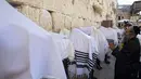 Pria Yahudi ultra-ortodoks dari kasta Cohanim Priestly berdoa dengan mengenakan selendang saat mereka berpartisipasi dalam pemberkatan selama hari raya Yahudi Sukkot di Tembok Barat, situs paling suci di Kota Tua Yerusalem, Rabu (22/9/2021).  (AP Photo/Sebastian Scheiner)
