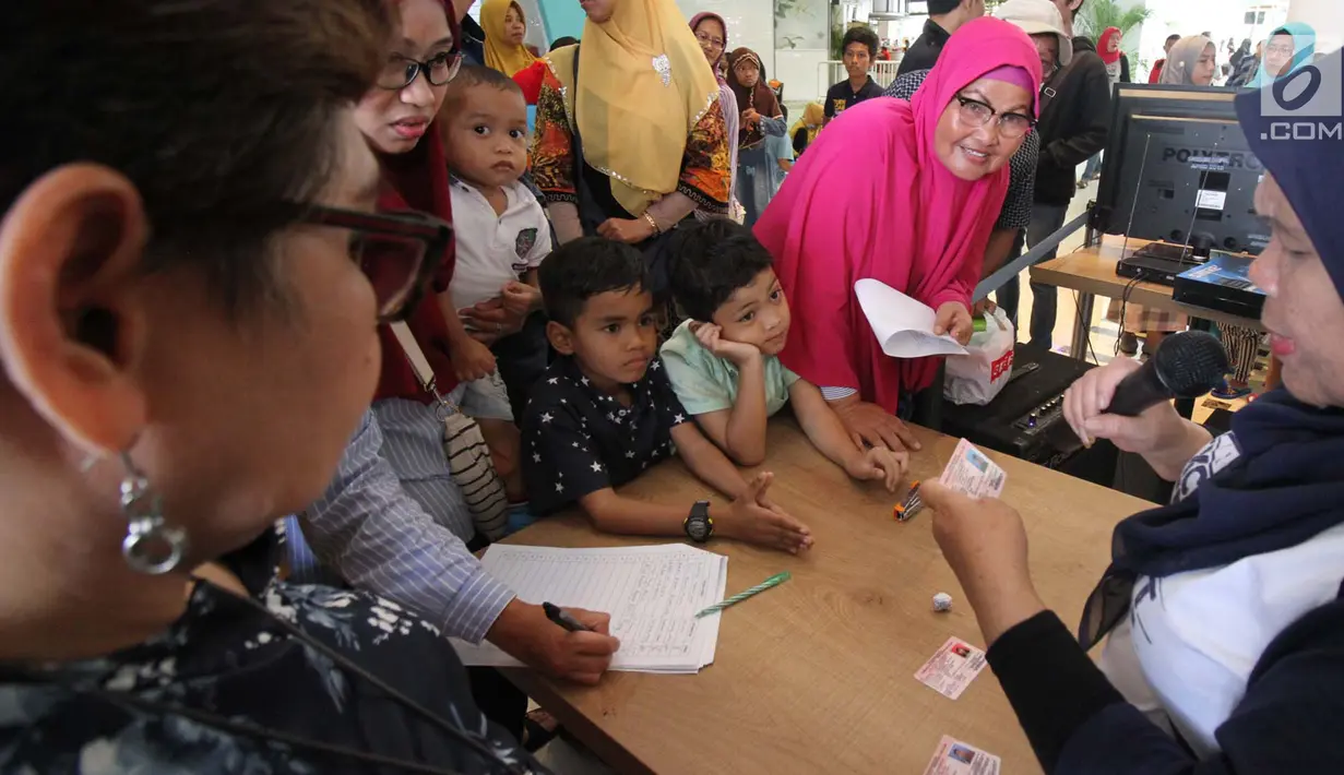 Petugas membagikan Kartu Identitas Anak (KIA)  yang sudah selesai dibuat di mal Living Wolrd Alam Sutera, Tangsel, Senin (17/12). Pembuatan KIA di mall itu untuk memudahkan masyarakat yang ingin mendaftarkan identitas anaknya. (Merdeka.com/Arie Basuki)