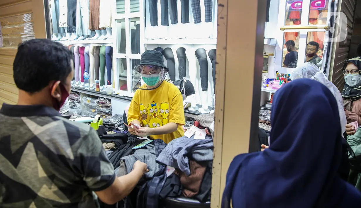 Pedagang melayani pembeli pakaian di salah satu kios Pasar Tanah Abang Blok A, Jakarta, Senin (15/6/2020). Setelah hampir tiga bulan ditutup, kawasan Pasar Tanah Abang kembali beroperasi pada Senin (15/6) diikuti dengan penerapan protokol kesehatan pencegahan Covid-19. (Liputan6.com/Faizal Fanani)