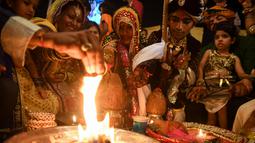 Sepasang pengantin menjalani ritual dalam prosesi pernikahan massal umat Hindu di Karachi, Pakistan, (19/3). Sebanyak 62 pasangan pengantin mengikuti pernikahan massal yang merupakan bagian dari perayaan Festival Holi.  (AFP Photo /Asif Hassan)