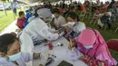 Dokter memeriksa kondisi warga di klinik vaksinasi massal darurat di lapangan sepak bola di Surabaya, Jawa Timur, Selasa (6/7/2021). Indonesia tengah memerangi gelombang infeksi baru yang belum pernah terjadi sebelumnya. (JUNI KRISWANTO/AFP)