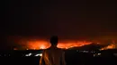 Seorang pria berdiri di pinggir jalan melihat kebakaran hutan di Anciao, Minggu (18/6). Kebakaran yang belum terkendali itu menjadi salah satu kebakaran hutan paling mematikan di Portugal dalam beberapa tahun terakhir. (PATRICIA DE MELO MOREIRA/AFP)