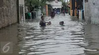 Warga menuntun anaknya melewati banjir yang mencapai pinggang orang dewasa di Rawa Buaya, Jakarta, Minggu (28/2/2016). Banjir terjadi akibat luapan Kali Mookervart yang diguyur hujan sejak malam. (Liputan6.com/Gempur M Surya)