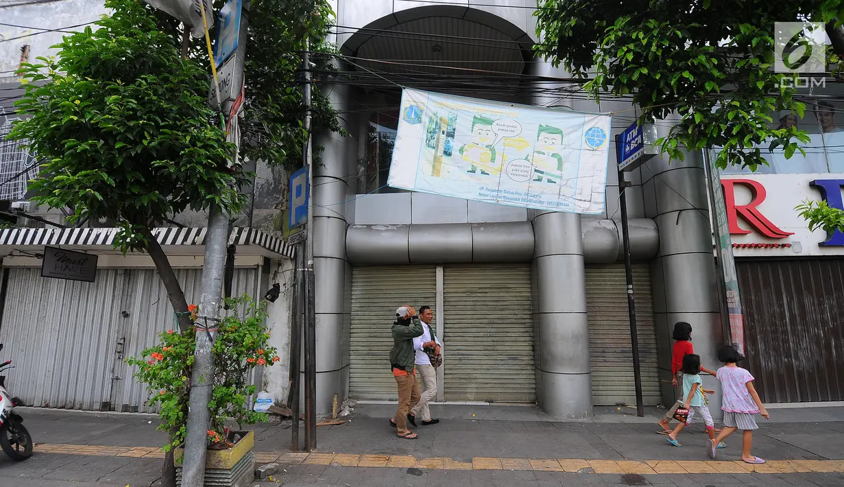 Pejalan kaki melintas di depan pertokoan yang tutup di Jalan Sabang, Jakarta pada Rabu (22/5/2019). Pemilik toko dan pengelola kantor di kawasan tersebut menutup toko dan kantor mereka imbas aksi 22 Mei 2019 yang berakhir rusuh di beberapa titik lokasi. (Liputan6.com/Aangga Yuniar)