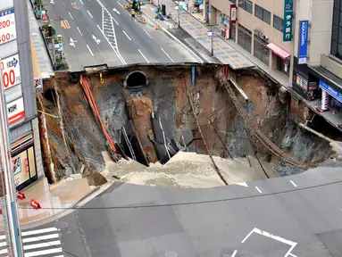 Sebuah lubang raksasa atau yang biasa disebut sinkhole tiba-tiba muncul di persimpangan dekat Stasiun Hakata, Fukuoka, Jepang, Selasa (8/11). Jalanan itu tiba-tiba runtuh hingga menciptakan lubang besar dan menghebohkan warga sekitar. (Kyodo/via REUTERS)